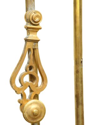 Polished brass cremone bolt with ornate teardrop-shaped center detail and round finials shown in close-up.