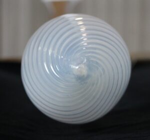 Close-up of a clear glass pendant light globe with swirled concentric ridges and a central fitter opening.