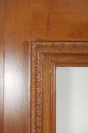 Close-up of an antique Victorian wooden mantel showing the shelf edge, ornate carved detail, and minor surface chips with a predrilled hole visible.