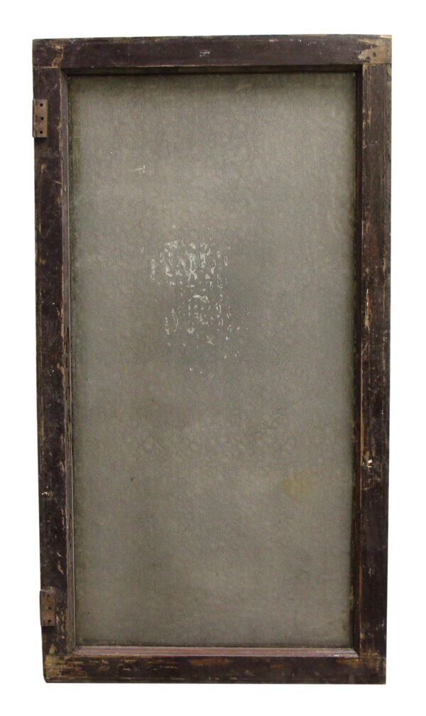 Worn wooden framed window with patterned glass and visible hinges, shown from the back side.