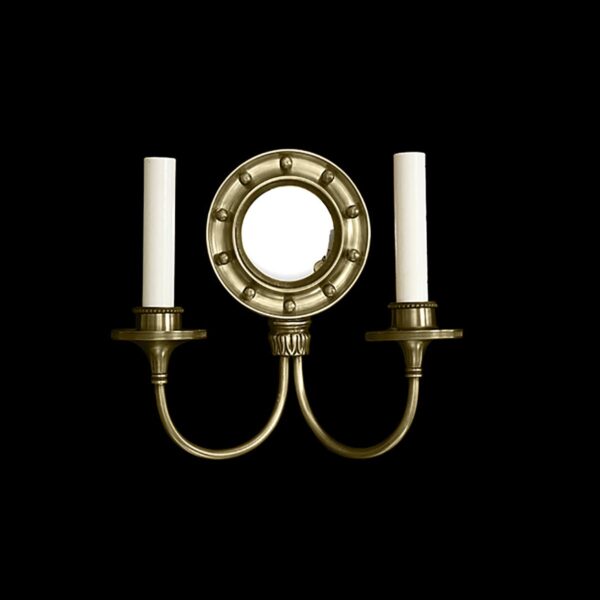Colonial brass wall sconce with two candle holders flanking a round convex mirror.