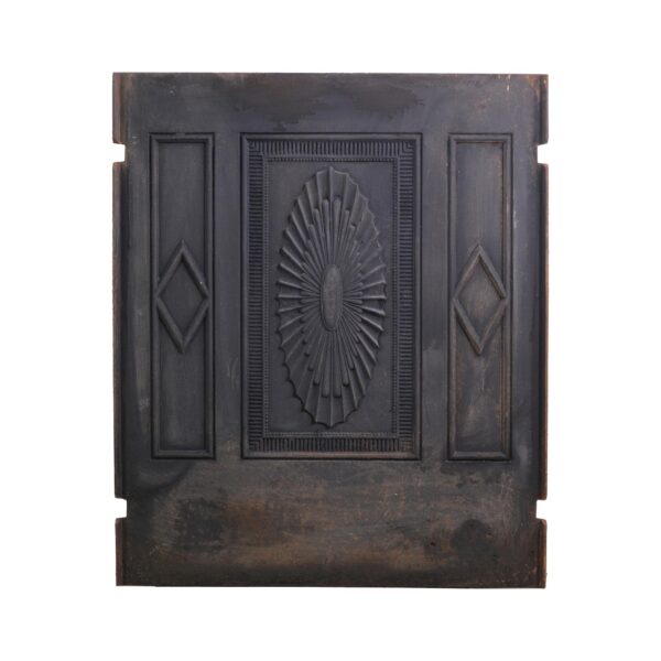 Antique Federal black cast iron fireplace fire back with a central sunburst relief, flanked by narrow side panels and visible wear along the edges.
