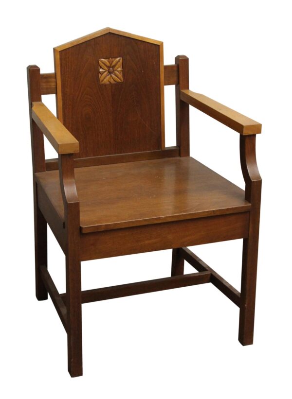 Mission style wooden chair with armrests, a carved floral motif on the backrest, and dark and light wood tones.