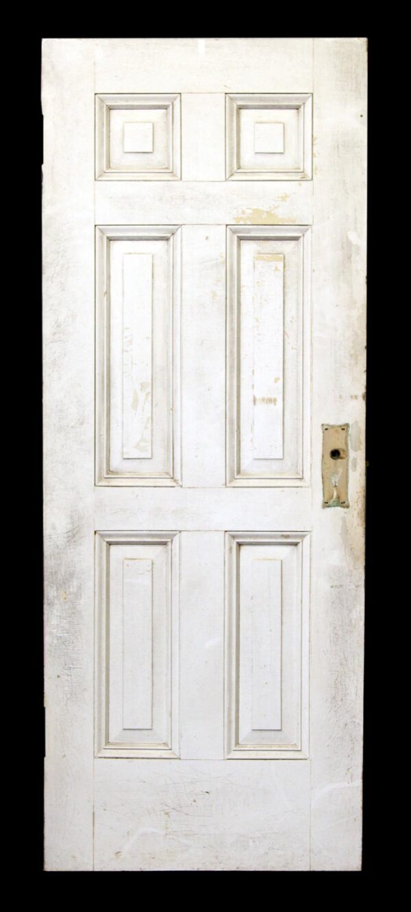 White six-panel wood door with a visible mortise lock plate on the right side.