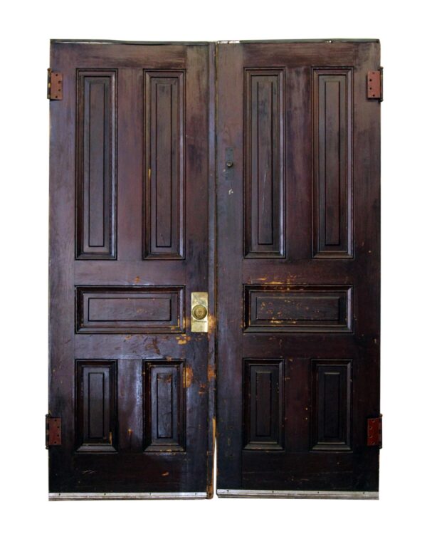 A pair of five-panel double doors in a dark wood tone with original hardware attached.
