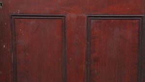 Close-up of a six-panel door with a dark wood tone and raised panel molding.