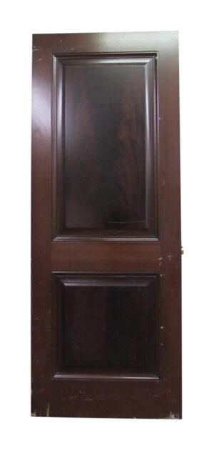 Two-panel dark wood door with raised rectangular panels and minor chips along the bottom edge.