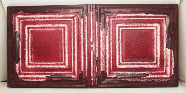 A reclaimed tin panel with two square raised patterns in red and white, shown horizontally.