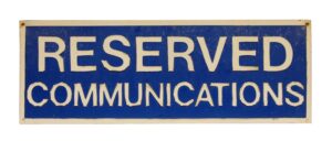 Blue and white metal sign reading Reserved Communications, with peeling letters and a rectangular shape.