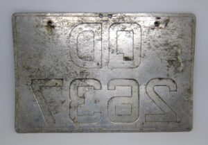 Metal sign plate with engraved lettering and four mounting holes, shown front on.