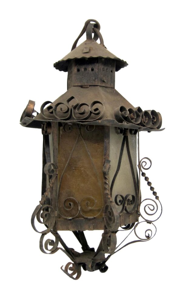 Antique-style ceiling lantern with cast iron frame, amber glass panels, and decorative scrollwork, shown hanging with the chain and canopy.