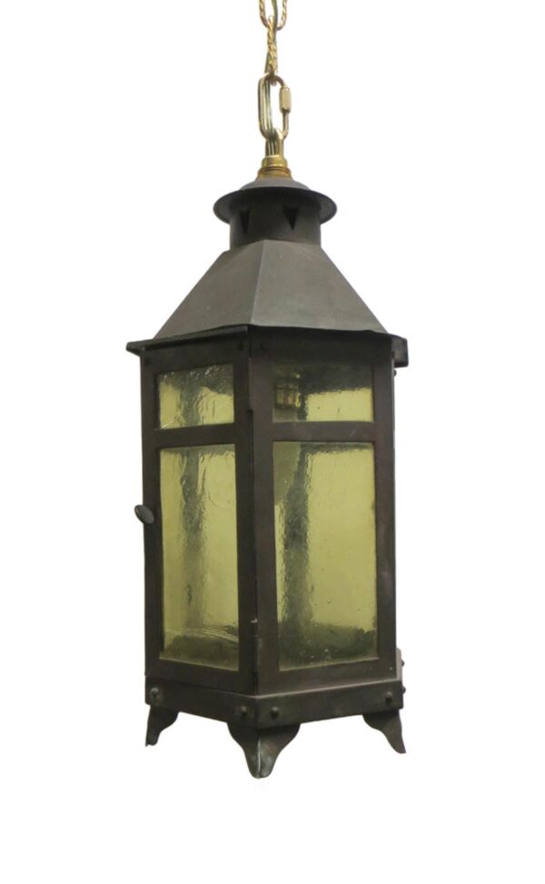 Arts and Crafts ceiling lantern with black wrought iron frame, amber glass panels, and a hanging chain.