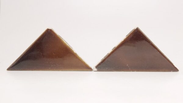 Two brown shiny ceramic triangle tiles with visible surface wear and small chips, shown side by side.