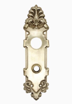 Victorian polished brass entry door back plate with ornate scrollwork, a large keyhole opening, and a circular knob hole in the center.