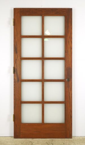 Vintage oak French door with ten frosted glass panes and brass hinges.