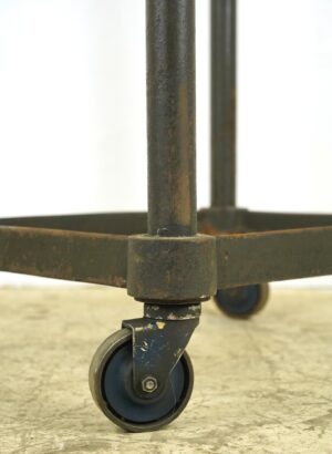 Close-up of a steel cart caster and leg, showing the worn base and bottom shelf support.
