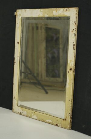Beveled mirror in a distressed tan and off-white steel frame, shown at a slight angle with worn paint and visible rust spots.