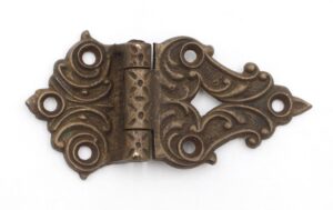 Victorian bronze offset hinge with ornate scrollwork and multiple screw holes, shown closed and angled to reveal the antique finish.