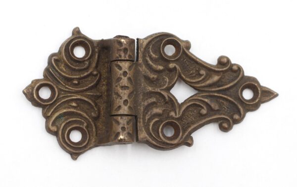 Victorian bronze offset hinge with ornate scrollwork and multiple screw holes, shown closed and angled to reveal the antique finish.