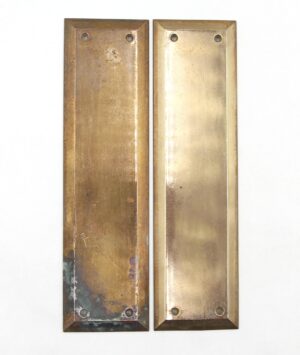 Pair of vintage push plates shown side by side, each with a beveled rectangular shape, four screw holes, and a polished brass finish, with visible wear and oxidation on the left plate.