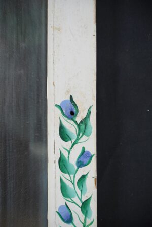 Close-up of a rectangular reclaimed window mirror with a white painted wooden frame and hand-painted blue and green rose stems along the lower section.