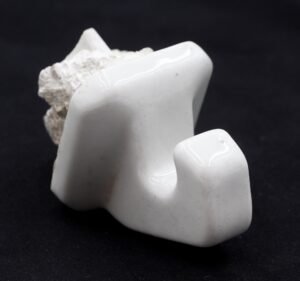 Vintage white ceramic wall hook with a single rounded hook and mortar on the back.