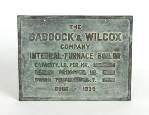 Rectangular bronze plaque with weathered verdigris finish and raised lettering for a Babcock & Wilcox integral-furnace boiler, showing two mounting holes and the built 1939 date.