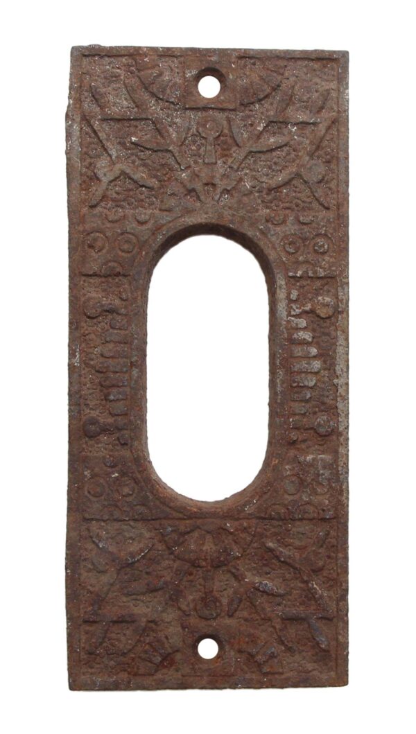 Cast iron pocket door plate in the Windsor pattern with an elongated center cutout and two screw holes, shown front on with a rusted patina and worn decorative detailing.
