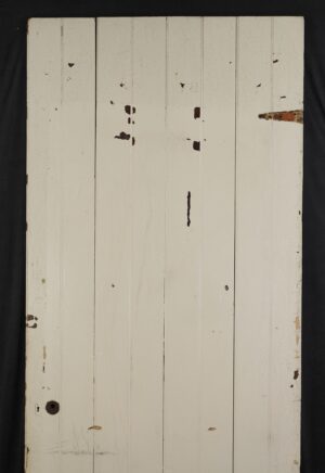 Antique four-board white wood passage door with visible paint wear and a left-hand out swing latch opening.