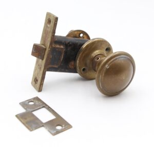 Vintage brass door knob set with round knob, two rosettes, mortise lock, strike plate, and spindle shown in a single product image.