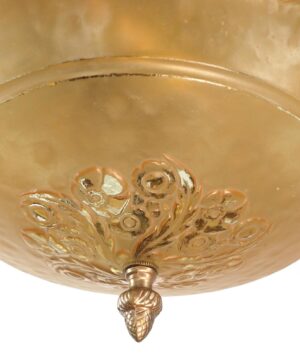 Close-up of an Art Deco chandelier shade with an amber frosted glass bowl and ornate antique bronze floral detail at the bottom.