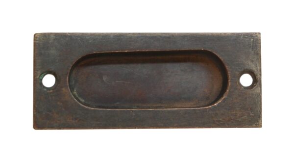 Antique bronze brass window sash lift with an oval recessed grip and two screw holes.