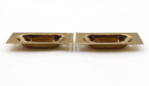 Pair of polished brass sash lifts shown side by side, each with a rectangular plate and recessed oval pull.