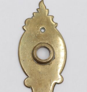 French-style brass door back plate with a polished finish, showing a round passage hole and a small keyhole opening, photographed front on.