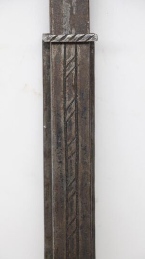 Close-up of a forged iron slide bolt with a twisted decorative top and vertical geometric detailing.