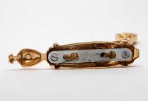 Polished brass towel bar bracket shown in close-up, with the mounting plate and screw holes visible from the side.