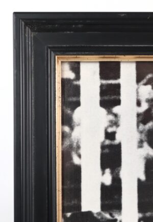 Close-up of a framed signed photograph showing the black painted wood frame, gold inner edge, and part of the black-and-white image inside.