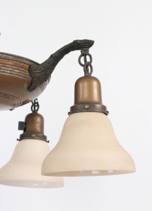 Close-up of a Colonial Revival brass chandelier showing two frosted glass shades, decorative arm details, and hanging chain links.