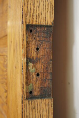 Close-up of the door edge showing weathered wood, several hinge screw holes, and worn antique hardware mortise.
