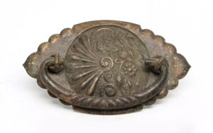 Victorian brass drawer bail pull with an antique patina and ornate oval backplate shown from the front.