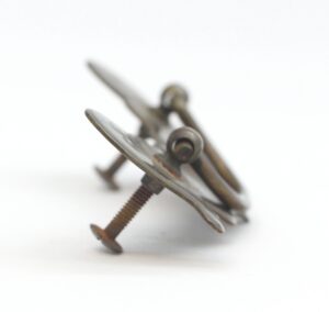 Close-up of a traditional bail drawer pull in antique brass finish, shown with the mounting screws and curved handle detail.