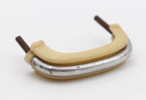 Mid century drawer pull in ivory plastic with a nickeled brass base and mounting screws visible at both ends.
