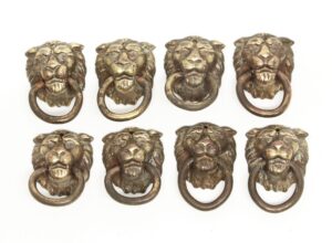 Set of Victorian brass lion head ring drawer pulls shown front-facing, each with an antique brass finish and visible age wear.