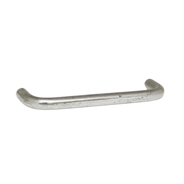Chrome drawer pull with a curved bar and rounded ends, shown in a close-up side view with visible age wear.