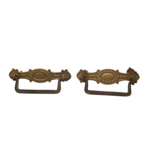 Pair of Victorian brass drawer bail pulls with a beaded oval center and worn antique finish.