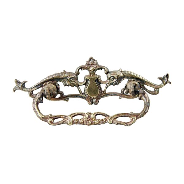 Ornate Victorian-style brass dresser bail pull with a cutout design and aged antique brass finish.