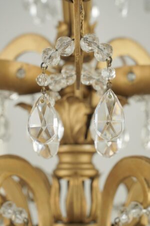 Close-up of a French Louis style chandelier with faceted crystal teardrops and rosettes on an antique bronze frame.