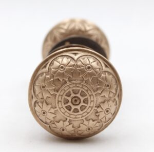 Ornate brass passage door knob with an engraved floral face and a round rosette visible behind it.