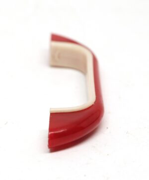 Mid century plastic bridge drawer pull in red and off white, shown in a close-up view with a curved handle profile.