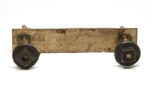 Antique brass bail drawer pull with two dark round knobs shown in close-up.